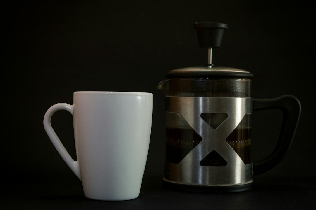 gray steel French press beside white ceramic mug